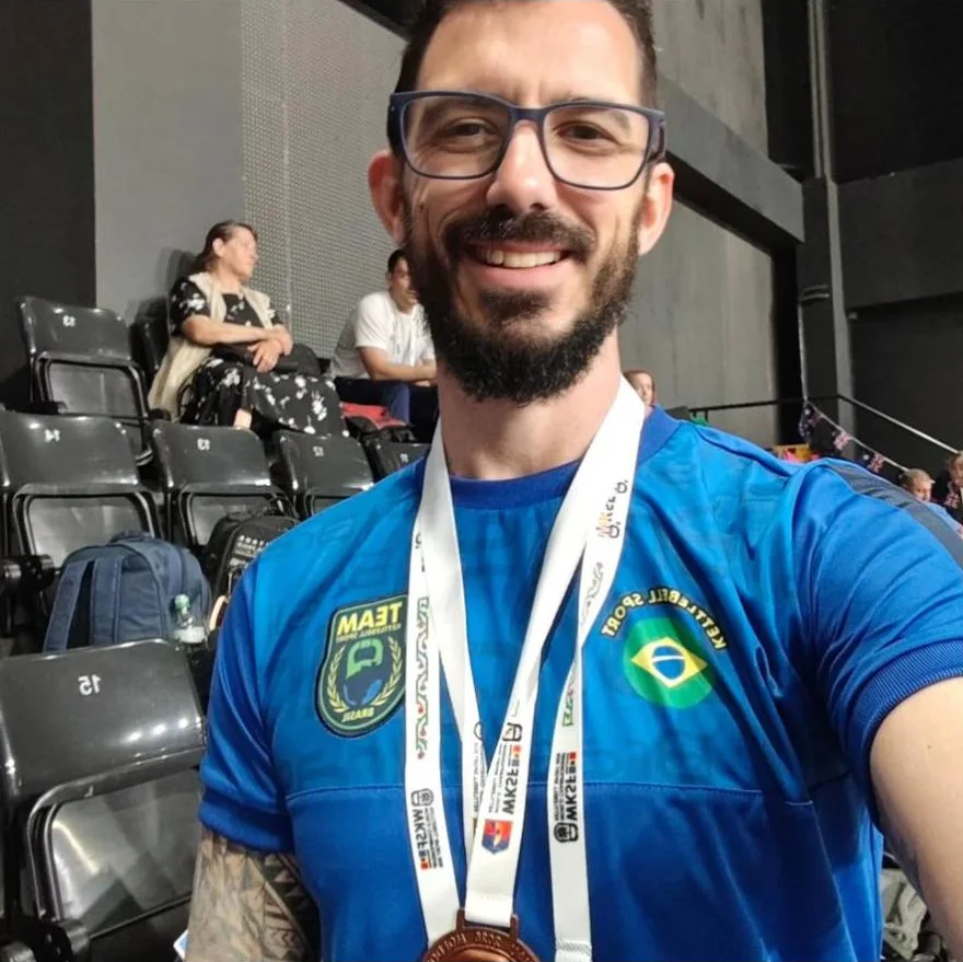 Treinador do UP sorrindo, com medalha no pescoço e camisa azul do Brasil